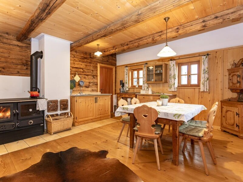 Kitchen and dining area, featuring a wood-burning stove, dining table, and wooden furniture.