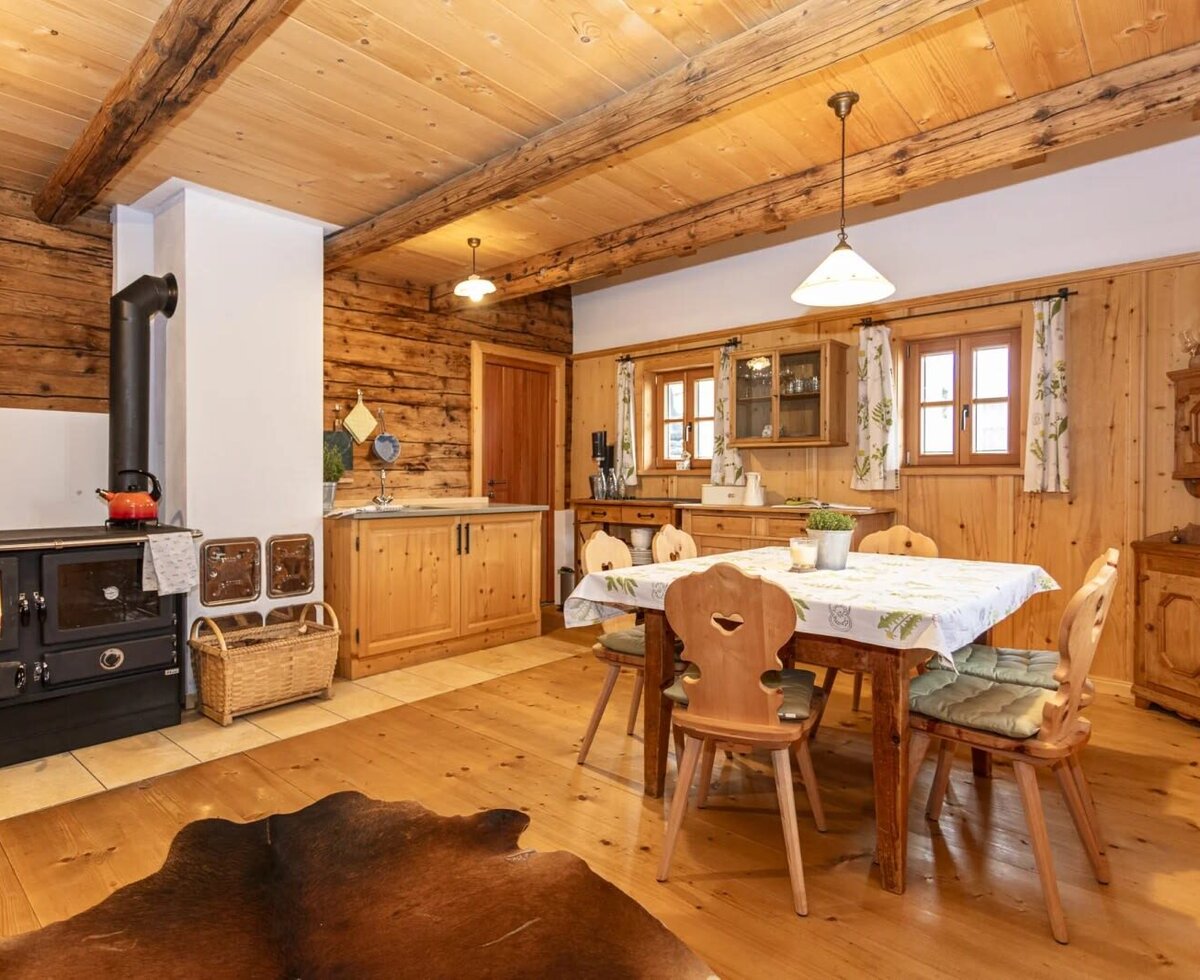 Kitchen and dining area, featuring a wood-burning stove, dining table, and wooden furniture.
