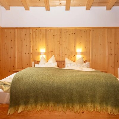 Bedroom featuring a double bed, wooden paneling, and exposed ceiling beams.