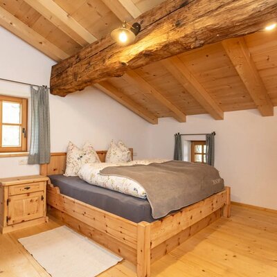 Bedroom with a double bed, wooden furniture, and exposed wooden beam ceiling.
