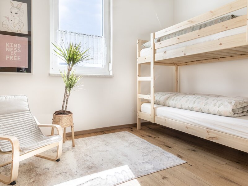 A bright room at our farm Bed and Breakfast featuring a wooden bunk bed and an armchair, ideal for families.