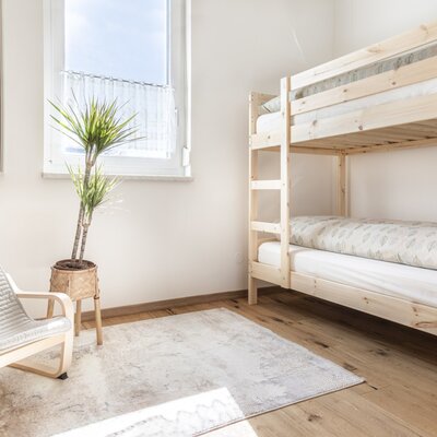 A bright room at our farm Bed and Breakfast featuring a wooden bunk bed and an armchair, ideal for families.