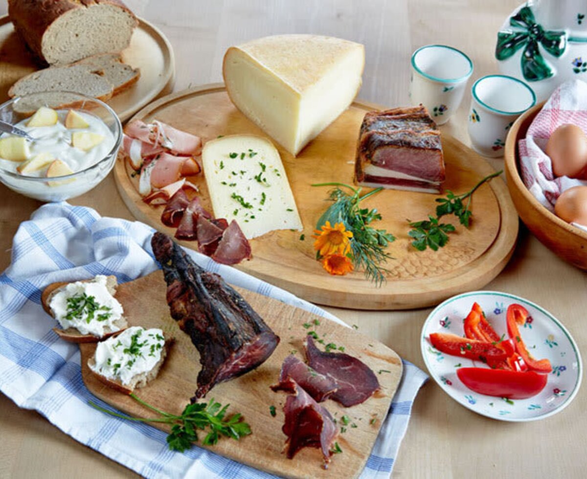 A traditional Farm House breakfast or snack spread featuring local cheeses, cured meats, fresh eggs, bread, and yogurt with fruit.