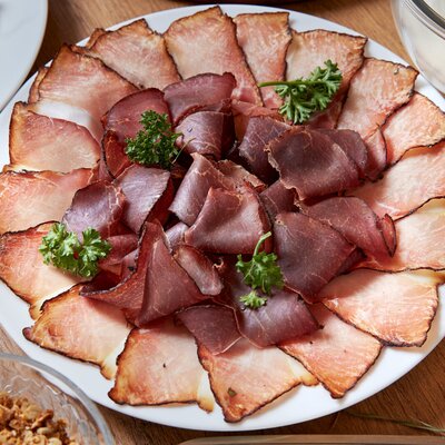 A selection of sliced cured meats, garnished with parsley, available at the Farm House.