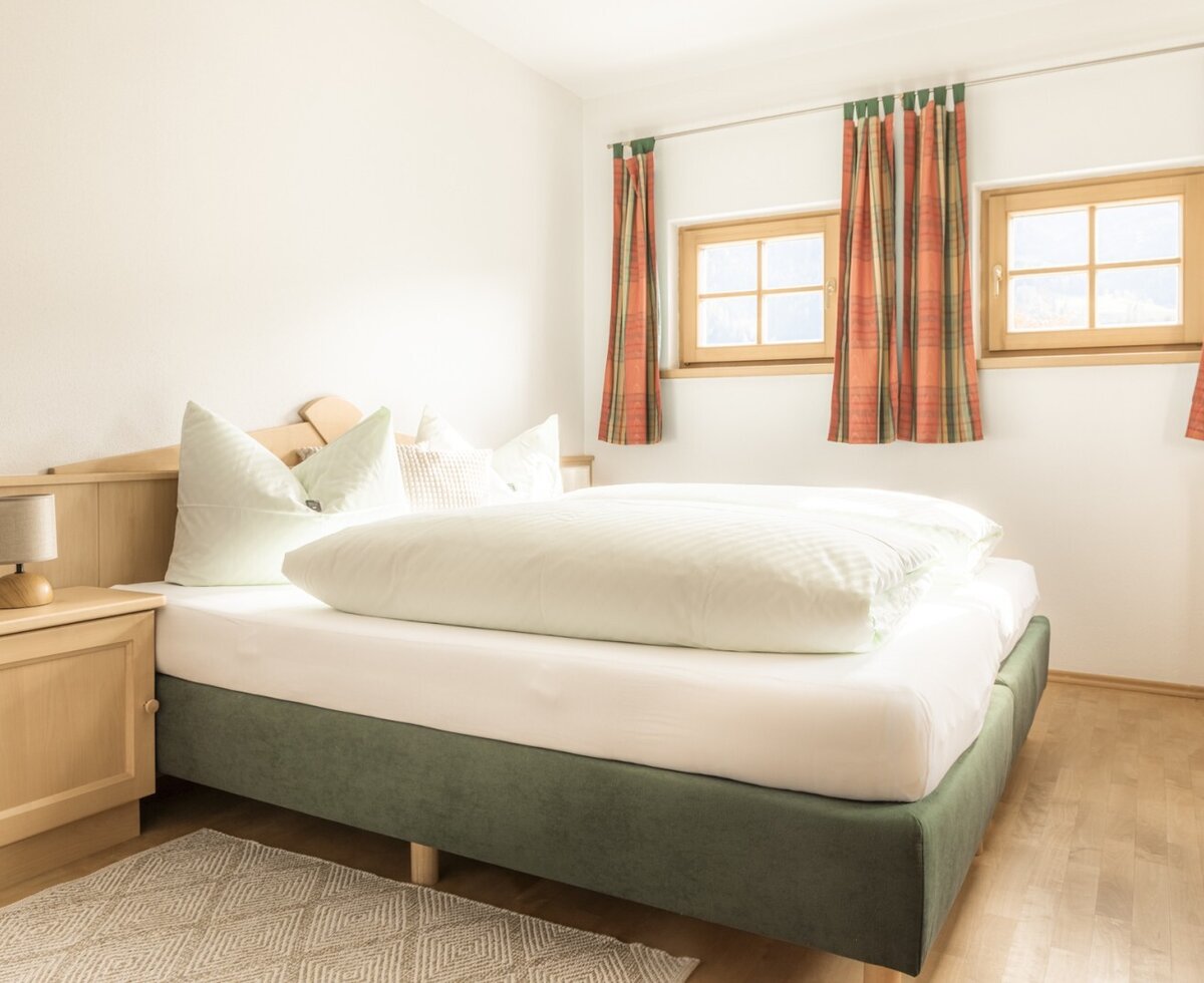 Double bedroom with a double bed, bedside table, and two windows.