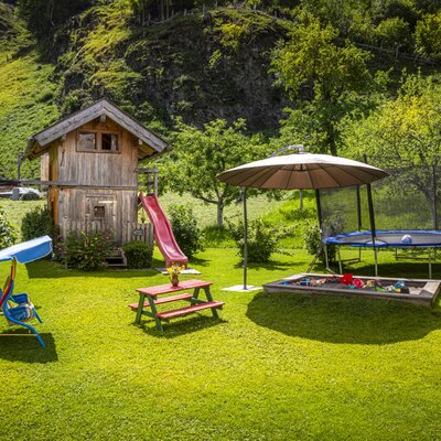The apartment's spacious garden features an inviting children's playground with a slide, trampoline, and sandbox surrounded by lush greenery.