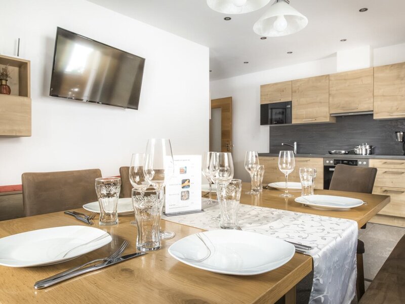 The dining area with a set table and television, adjacent to the fully equipped kitchen.