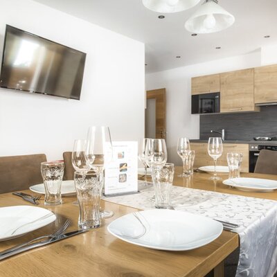 The dining area with a set table and television, adjacent to the fully equipped kitchen.