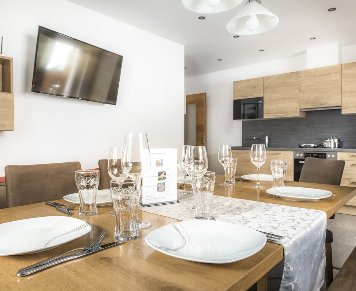 The dining area with a set table and television, adjacent to the fully equipped kitchen.