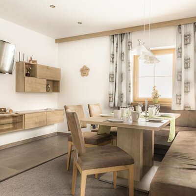 Dining area  with a dining table, corner bench, chairs, television, and wooden furniture.