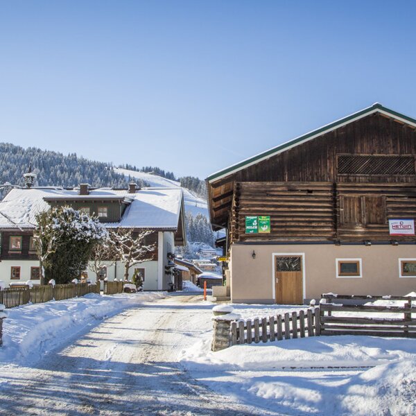 The farm house with snow-covered buildings and a winter mountain landscape in the background.