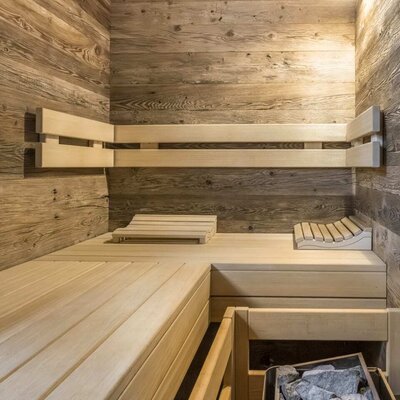 Sauna in the Ferienwohnung featuring wooden walls, benches, and a sauna heater.