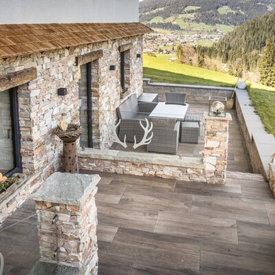 The Ferienwohnung's terrace features an outdoor seating area and panoramic views of the valley and surrounding mountains.