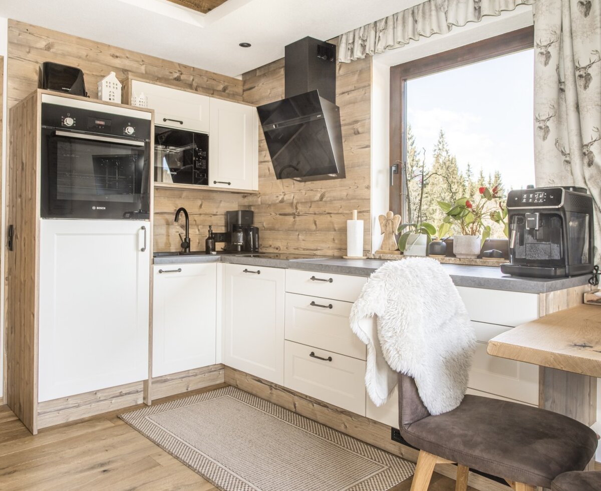 Modern kitchen in the Ferienwohnung with an oven, microwave, coffee machine, and dining area.