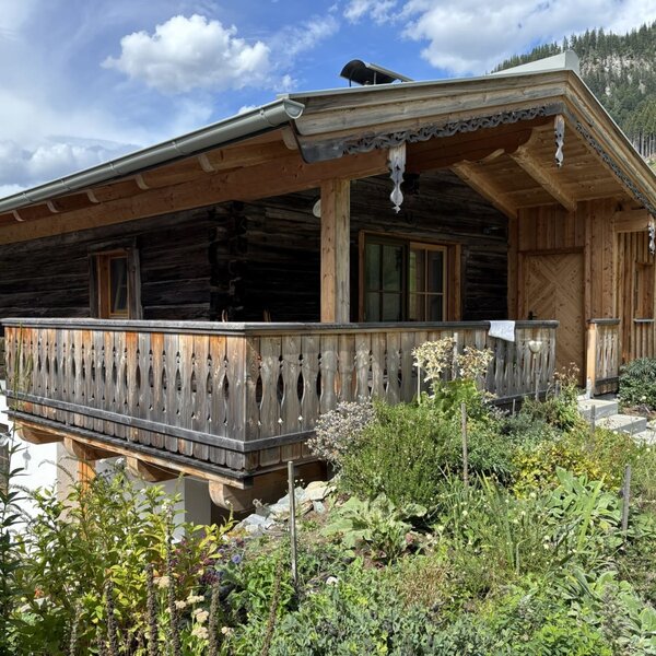 A charming apartment in a traditional wooden style, featuring an inviting balcony and lush greenery.
