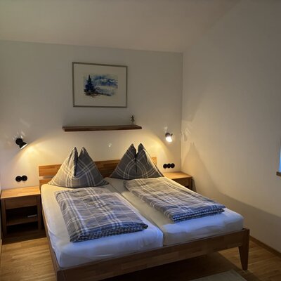 A cozy bedroom in the apartment featuring an inviting double bed, warm reading lamps, and wooden accents.