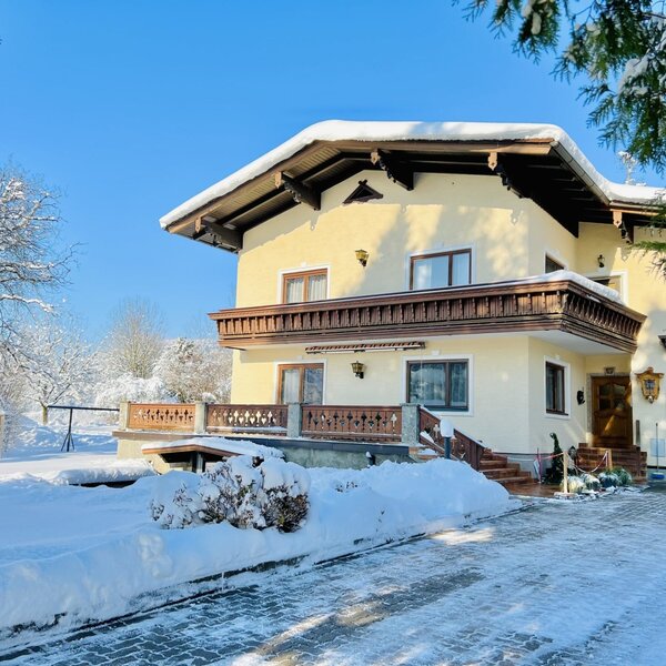 The Wallmerhof farmhouse exterior, featuring traditional wooden balconies and snow-covered surroundings.