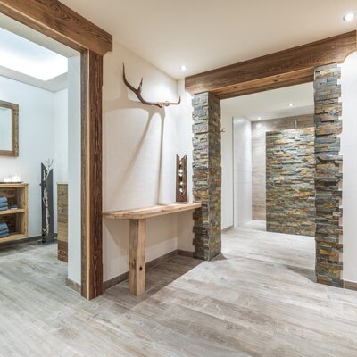The Farm House hallway, featuring wood and stone accents, provides access to a bathroom with fresh towels and a separate shower area.