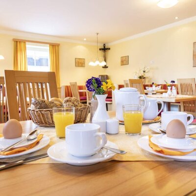 Breakfast service in the farm house dining room, with tables set with eggs, orange juice, and fresh bread.