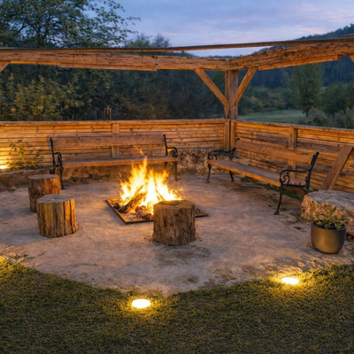 Outdoor fire pit with a burning fire, wooden benches, and a wooden pergola at the farmhouse.