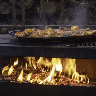 Outdoor barbecue at the Farm House, cooking meat and corn on a griddle over an open fire.