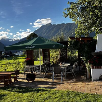 The farmhouse's inviting outdoor terrace with comfortable seating, a brick fireplace, and scenic mountain views.