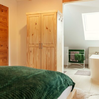 Bedroom 2 with a wooden wardrobe and an adjacent bathroom featuring a bathtub and a skylight.