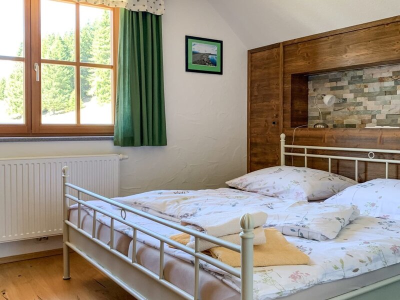 Bedroom in the Bed and Breakfast with a double bed, wooden floor, exposed wooden beam, and a window overlooking trees.