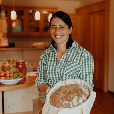 A hostess at the Farm House presenting a freshly baked loaf of bread.