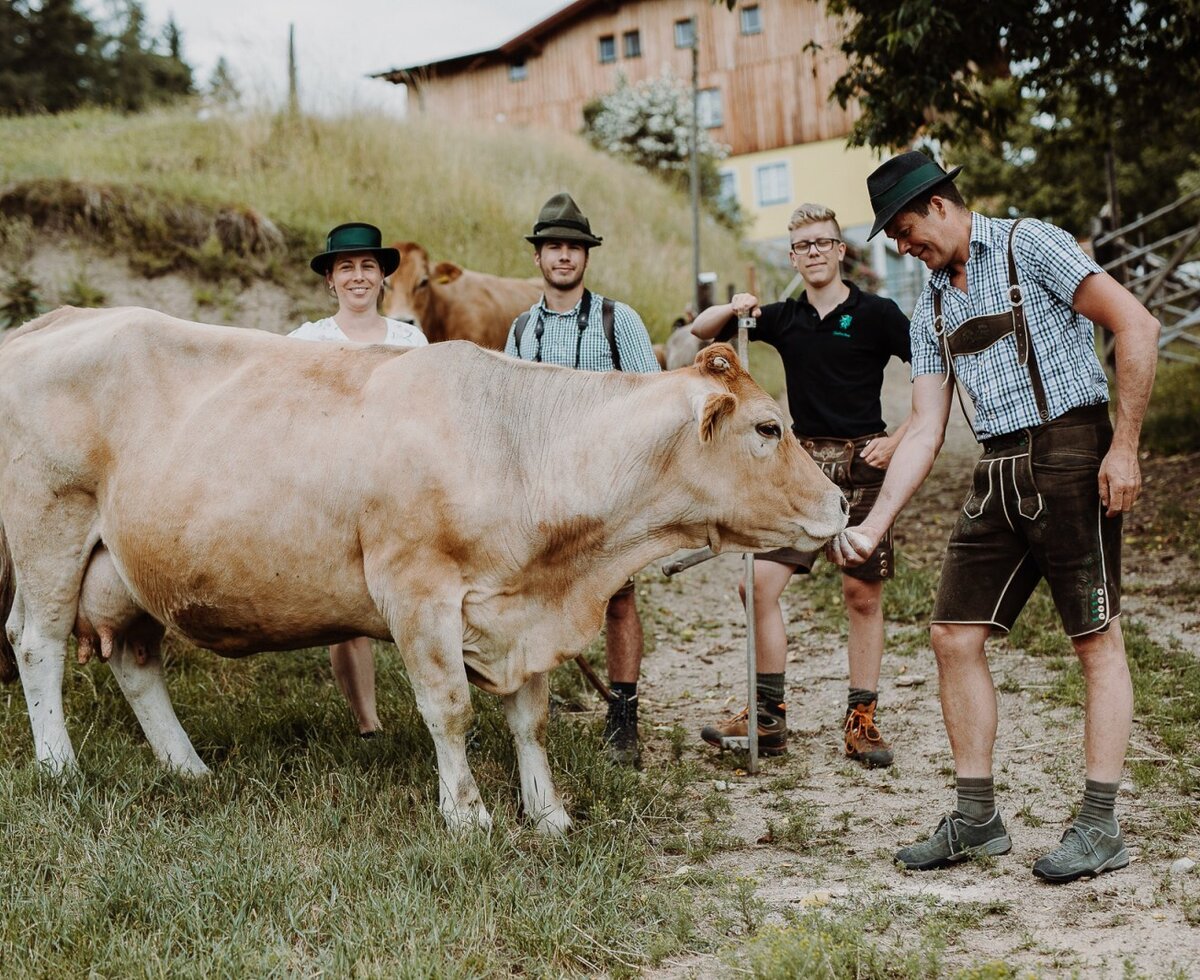 People in traditional clothing feeding a cow on the grounds of the Farm House.