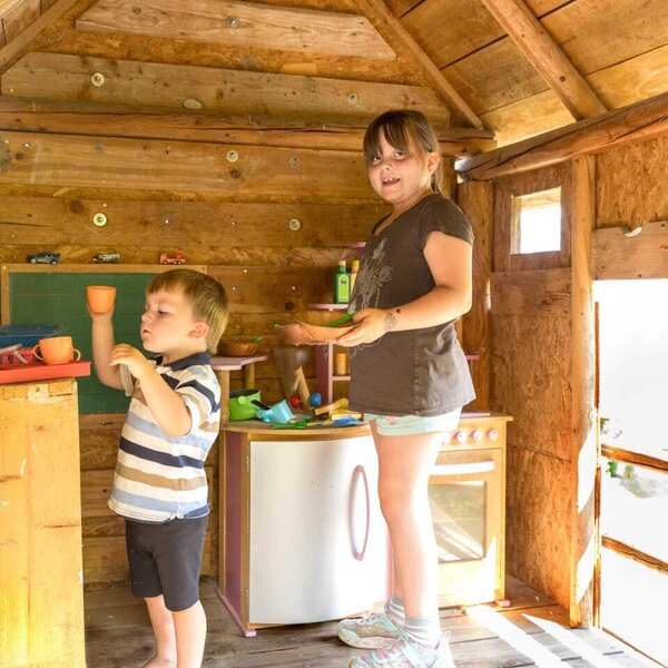 A cozy wooden playhouse at the farmhouse, equipped with a fun toy kitchen for young guests.