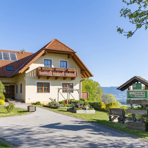 Exterior view of the farmhouse with balconies, solar panels on the roof, and a 'Holiday on the Farm' sign.