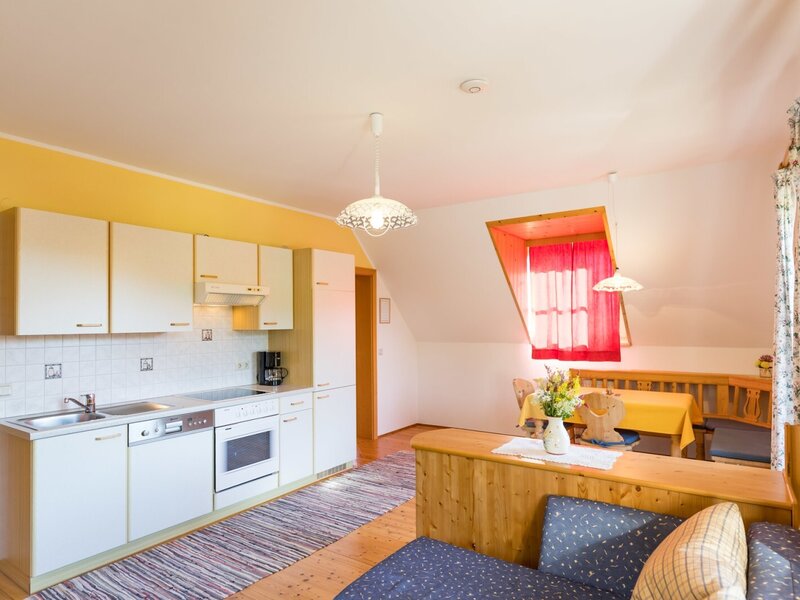 The living kitchen in the farmhouse, featuring a kitchen block, dining area, and double sofa.