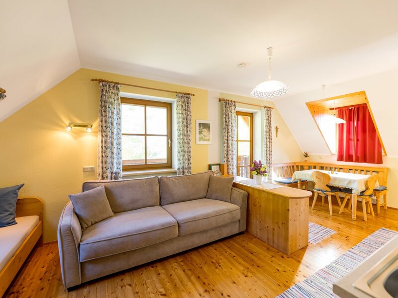 Eat-in kitchen of the farmhouse apartment, featuring a double sofa, extra bed, seating area, kitchen block, and balcony access.
