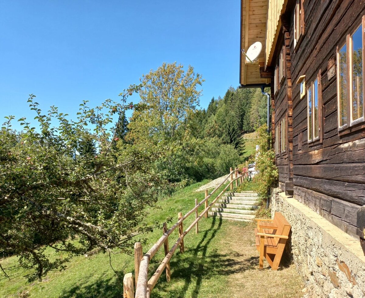 The farmhouse exterior features a wooden bench, a fenced pathway with stairs, and an adjacent apple tree.