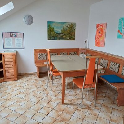 The recreation room in the farm house features a corner bench dining area with a table and wooden storage cabinets.