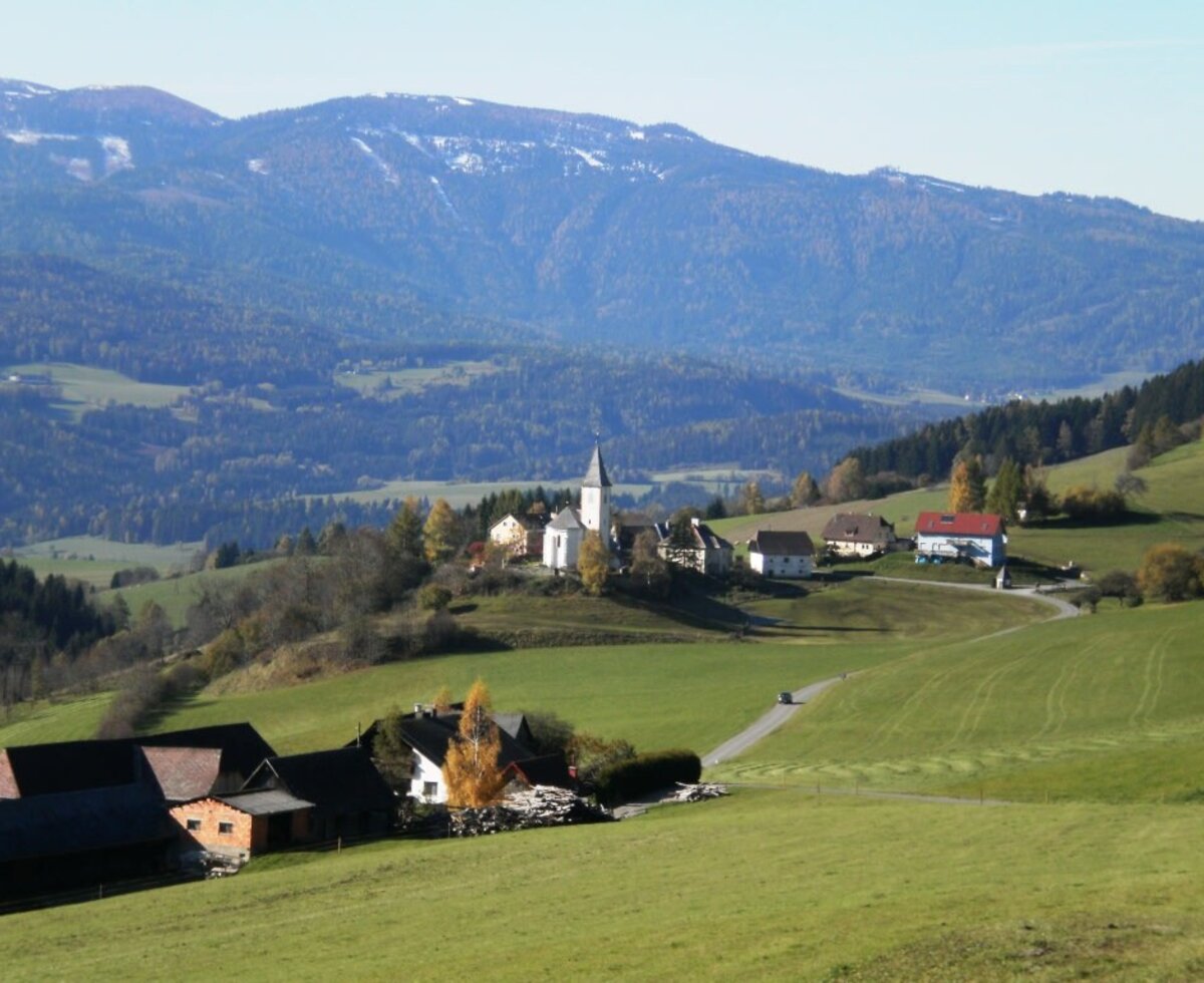 The surrounding landscape of the Farm House, featuring a village with a church, green fields, and mountains.