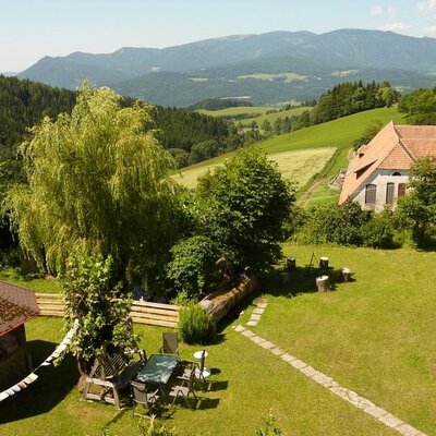 The Farm House features a garden with a lawn, outdoor seating, and a gazebo, offering views of rolling green hills and distant mountains.