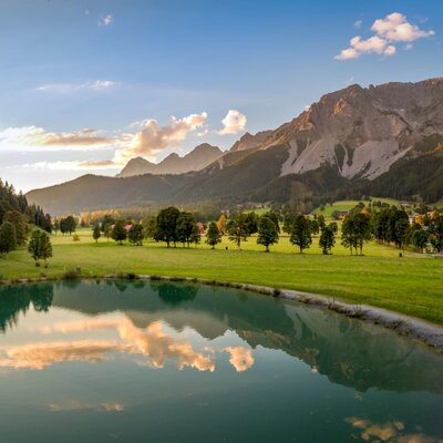 Scenic view from the Bauernhof overlooking the quiet lake, green meadows, and impressive mountain backdrop.
