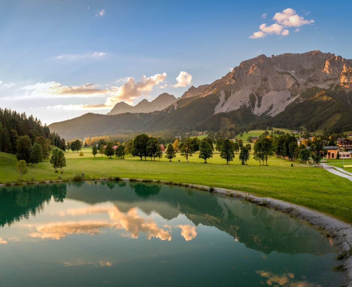 Scenic view from the Bauernhof overlooking the quiet lake, green meadows, and impressive mountain backdrop.