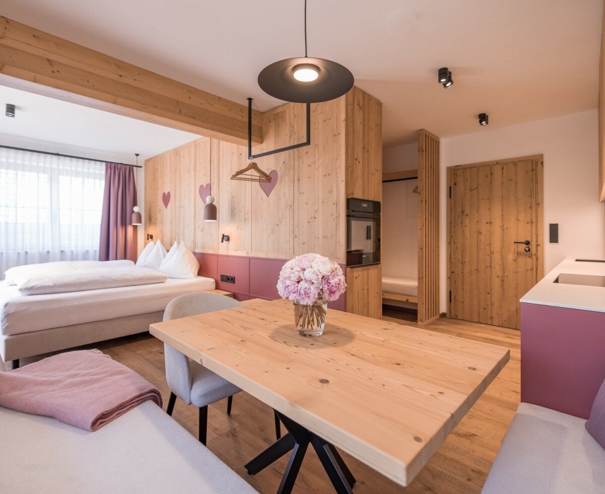 A cozy living and sleeping area at the apartment Frieda, featuring modern solid wood furniture and an inviting dining nook.