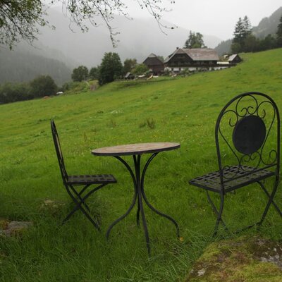 Outdoor seating with a metal table and chairs on the farmhouse meadow, offering mountain views.