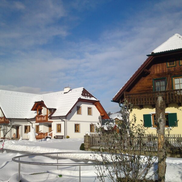 Farm House exterior during winter, with snow-covered roofs and balconies.