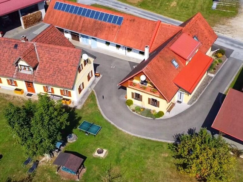 Aerial view of the Farm House property, showing the complex of buildings, a spacious garden with a ping-pong table, and a carport.