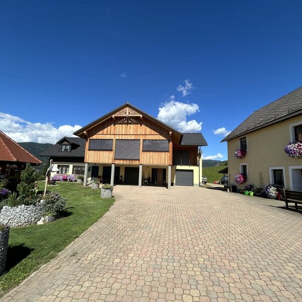 The exterior of the farmhouse, featuring a paved courtyard, the various buildings, and a garden with a gazebo.
