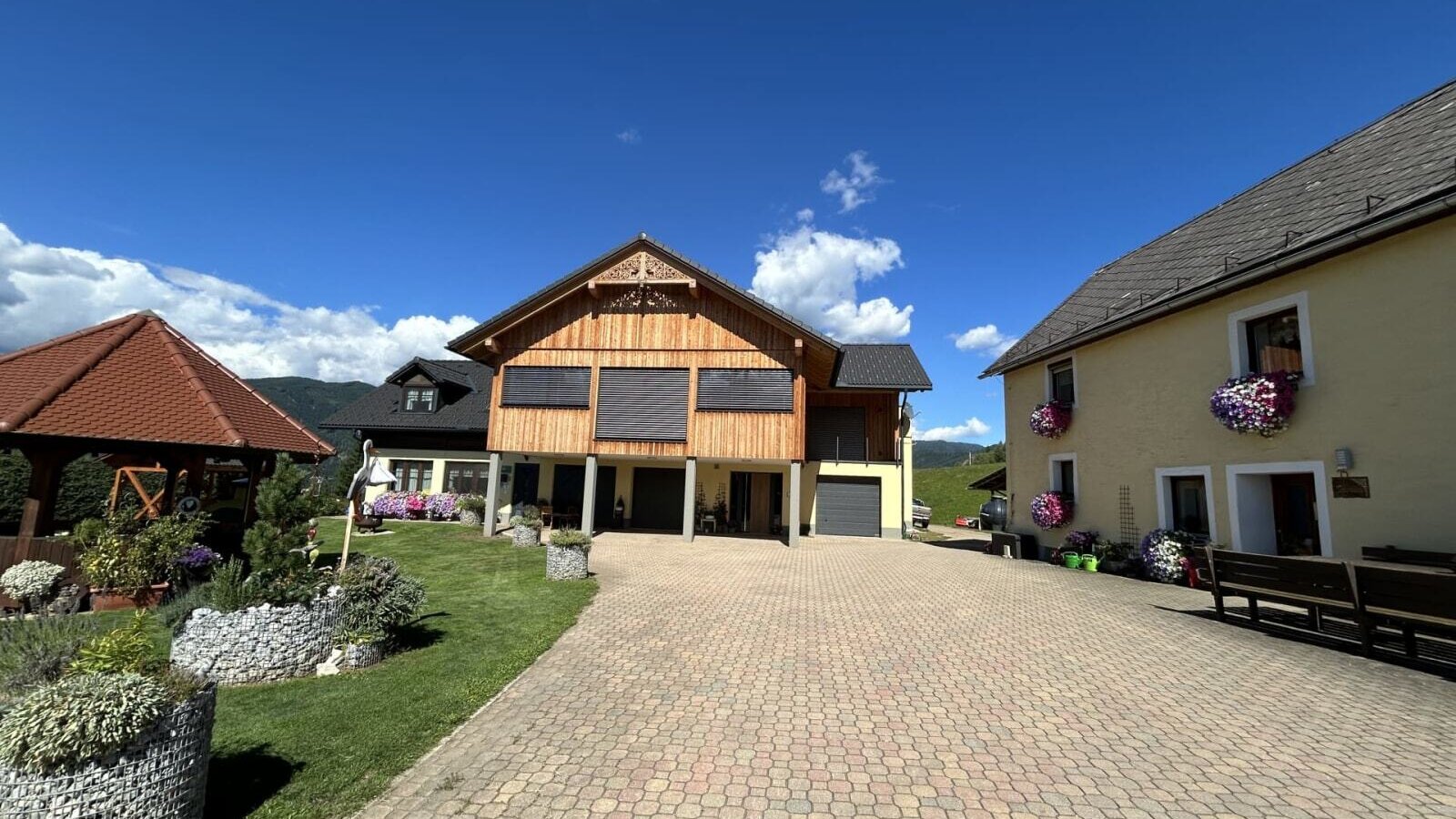 The exterior of the farmhouse, featuring a paved courtyard, the various buildings, and a garden with a gazebo.