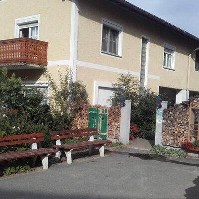 The front of the Farm House, featuring a wooden balcony and two outdoor benches.