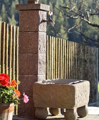 Stone pillar with water tap in the outdoor area of the farmhouse.