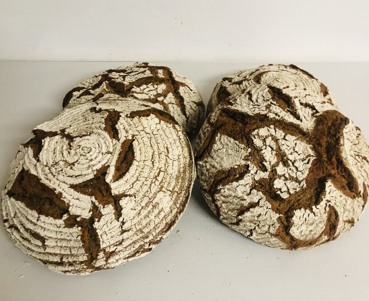 Four loaves of rustic farmhouse bread with a floury, cracked crust, as part of the culinary offerings at the farmhouse.