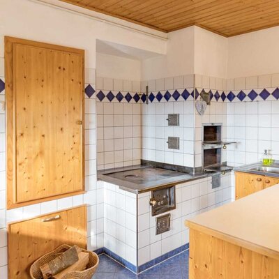 The farmhouse's rustic kitchen featuring a traditional wood-burning stove and cozy wooden paneling.